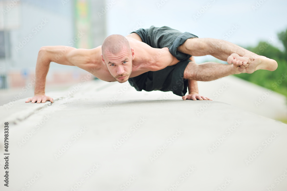 Young caucasian male practicing yoga on the city streets
