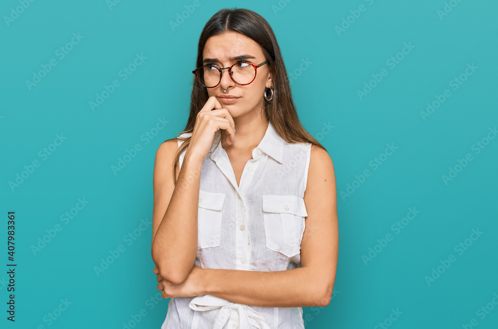 Young hispanic woman wearing casual clothes serious face thinking about question with hand on chin, thoughtful about confusing idea Young hispanic woman wearing casual clothes serious face thinking about question with hand on chin, thoughtful about confusing idea