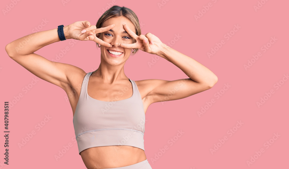 Beautiful caucasian woman wearing sportswear doing peace symbol with fingers over face, smiling cheerful showing victory - obrazy, fototapety, plakaty 