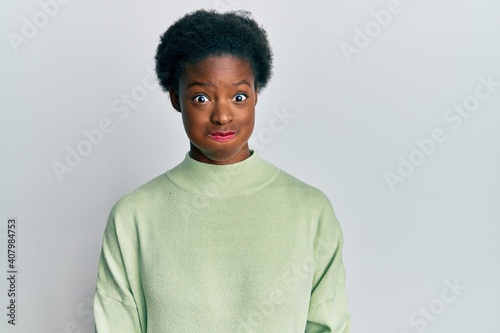 Young african american girl wearing casual clothes puffing cheeks with funny face. mouth inflated with air, crazy expression.