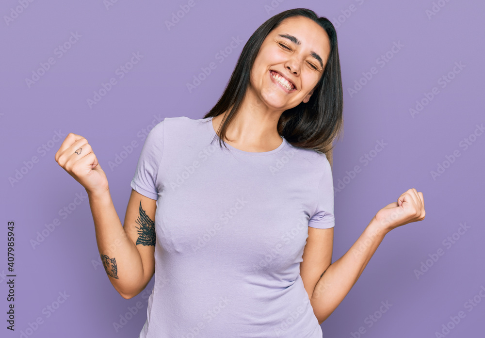 Young hispanic woman wearing casual clothes very happy and excited doing winner gesture with arms raised, smiling and screaming for success. celebration concept. Young hispanic woman wearing casual clothes very happy and excited doing winner gesture with arms raised, smiling and screaming for success. celebration concept.