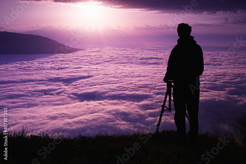 Silhouette of a professional landscape photographer in the mountains at sunset.