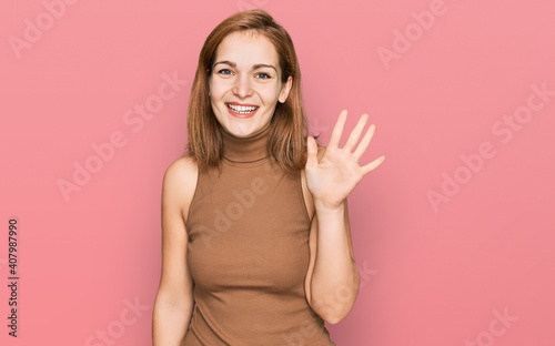 Young caucasian woman wearing casual clothes showing and pointing up with fingers number five while smiling confident and happy. © Krakenimages.com