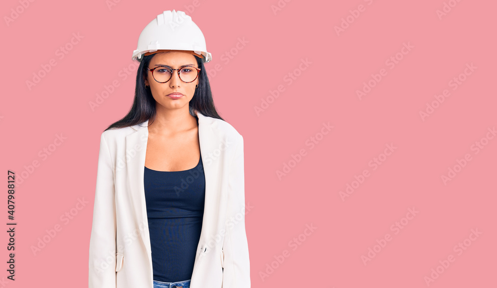 Young beautiful latin girl wearing architect hardhat and glasses depressed and worry for distress, crying angry and afraid. sad expression. Young beautiful latin girl wearing architect hardhat and glasses depressed and worry for distress, crying angry and afraid. sad expression.