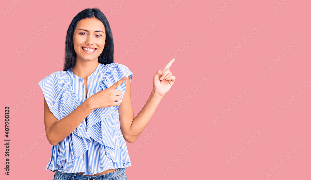 Young beautiful latin girl wearing casual clothes smiling and looking at the camera pointing with two hands and fingers to the side. Young beautiful latin girl wearing casual clothes smiling and looking at the camera pointing with two hands and fingers to the side.