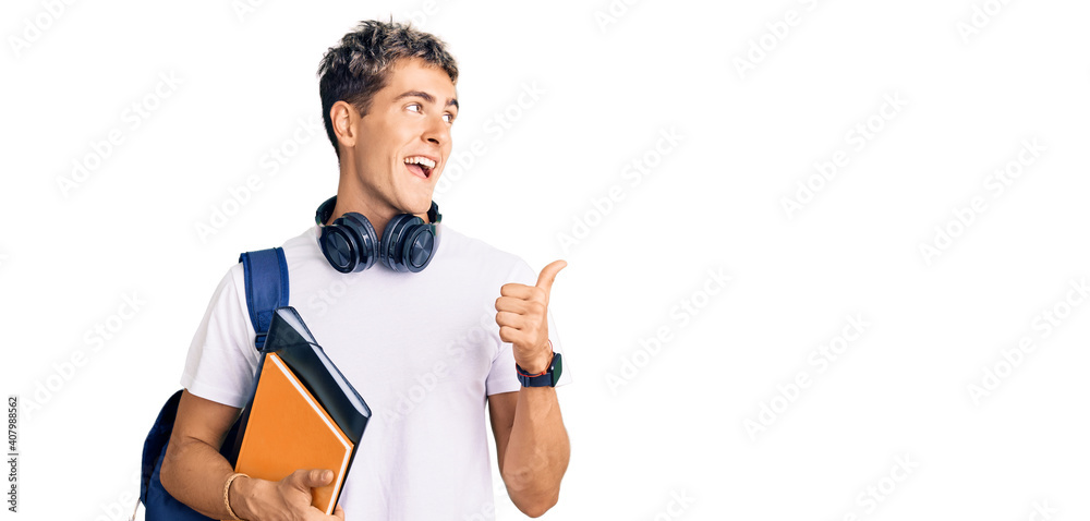 Young handsome man holding student backpack and books pointing thumb up to the side smiling happy with open mouth Young handsome man holding student backpack and books pointing thumb up to the side smiling happy with open mouth