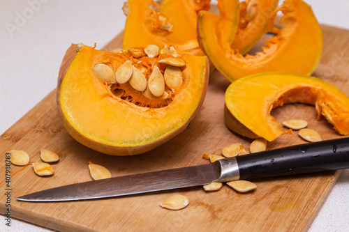 Cutting pumpkin vegetable with seeds on wooden board. Cooking healthy vegetarian food at home