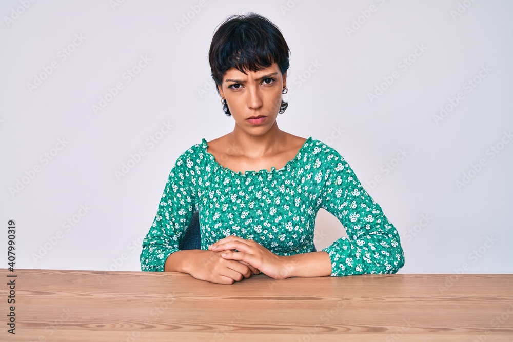 Beautiful brunettte woman wearing casual clothes sitting on the table skeptic and nervous, frowning upset because of problem. negative person. Beautiful brunettte woman wearing casual clothes sitting on the table skeptic and nervous, frowning upset because of problem. negative person.