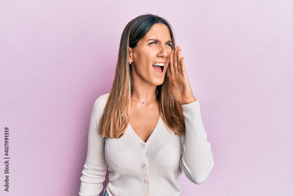 Brunette young woman wearing casual clothes shouting and screaming loud to side with hand on mouth. communication concept. Brunette young woman wearing casual clothes shouting and screaming loud to side with hand on mouth. communication concept.
