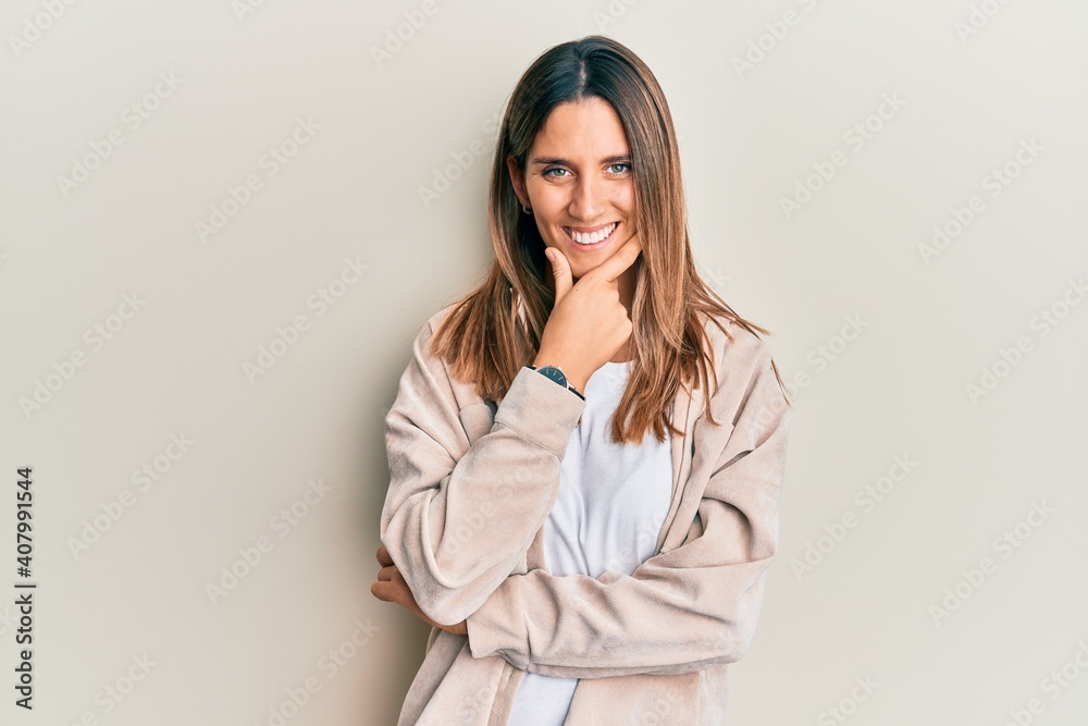 Brunette young woman wearing casual clothes looking confident at the camera smiling with crossed arms and hand raised on chin. thinking positive.