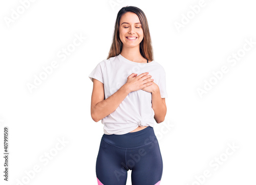 Young beautiful girl wearing casual t shirt smiling with hands on chest with closed eyes and grateful gesture on face. health concept.