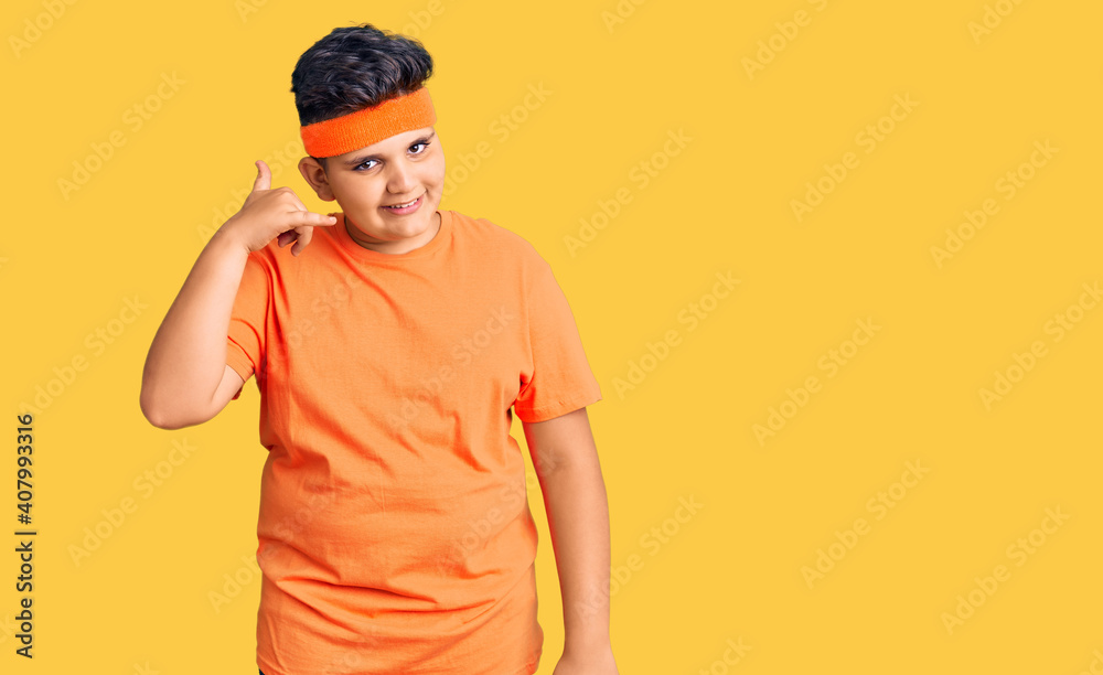 Little boy kid wearing sportswear smiling doing phone gesture with hand and fingers like talking on the telephone. communicating concepts. Little boy kid wearing sportswear smiling doing phone gesture with hand and fingers like talking on the telephone. communicating concepts.