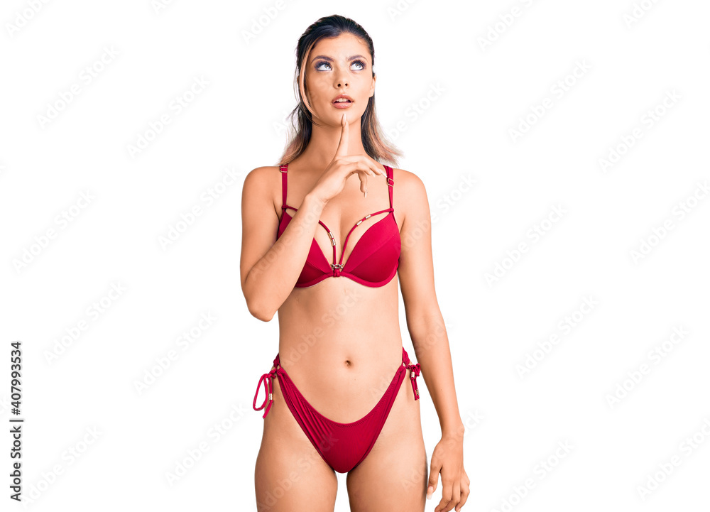 Naklejka premium Young beautiful woman wearing bikini thinking concentrated about doubt with finger on chin and looking up wondering