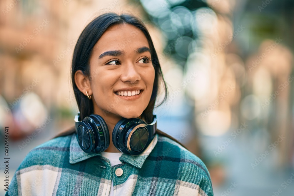Young latin girl smiling happy using headphones at the city. Young latin girl smiling happy using headphones at the city.