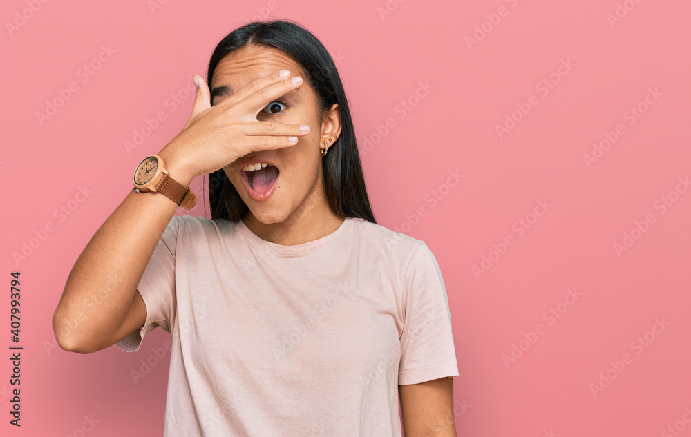 Young asian woman wearing casual clothes peeking in shock covering face and eyes with hand, looking through fingers with embarrassed expression. Young asian woman wearing casual clothes peeking in shock covering face and eyes with hand, looking through fingers with embarrassed expression.