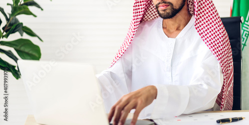 Handsome confident arab businessman working and looking at technology of laptop computer monitor.Creative coworkers arabic business people thinking and planning at modern work loft
