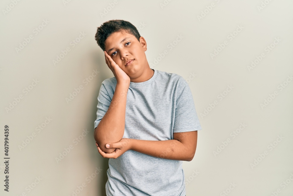 Teenager hispanic boy wearing casual grey t shirt thinking looking tired and bored with depression problems with crossed arms. Teenager hispanic boy wearing casual grey t shirt thinking looking tired and bored with depression problems with crossed arms.