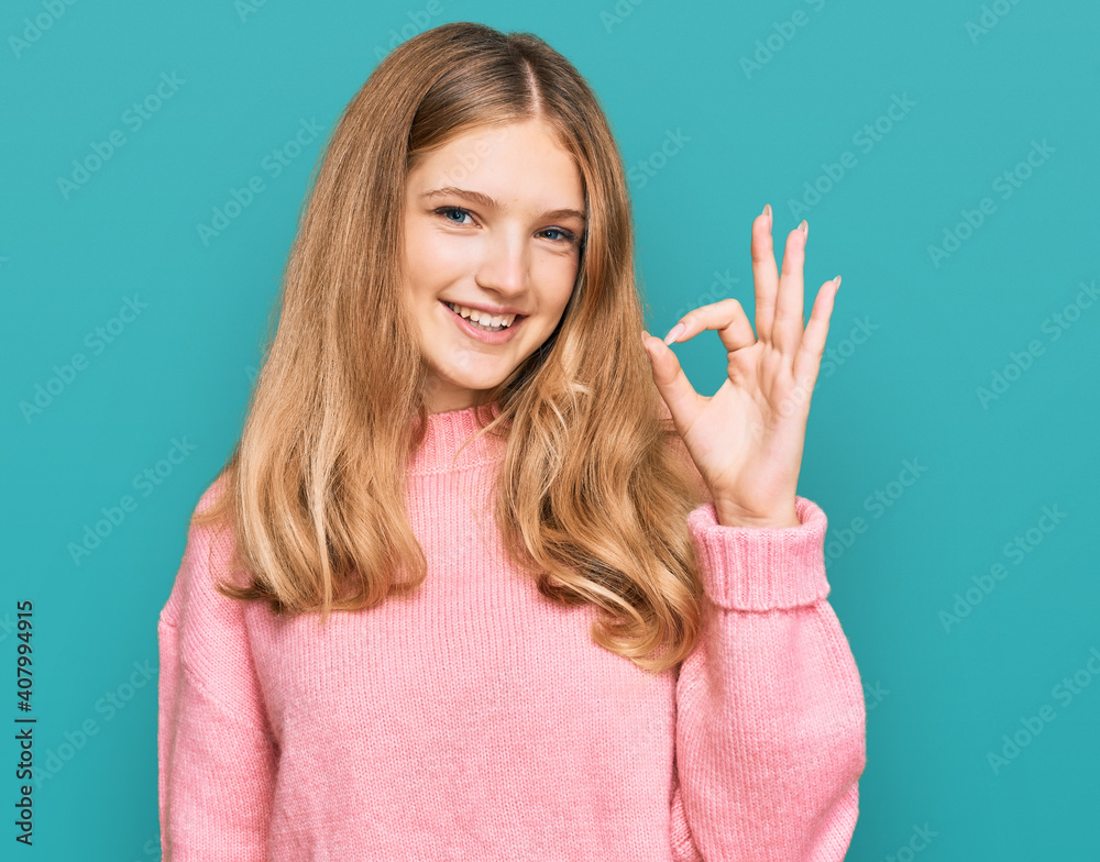 Beautiful young caucasian girl wearing casual winter sweater smiling positive doing ok sign with hand and fingers. successful expression. Beautiful young caucasian girl wearing casual winter sweater smiling positive doing ok sign with hand and fingers. successful expression.