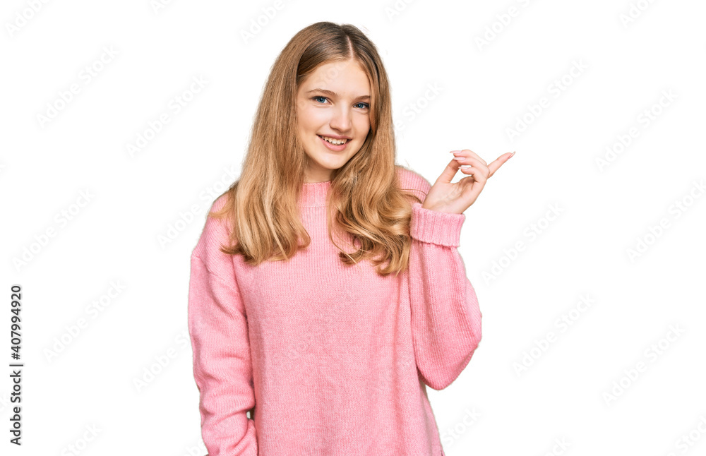 Beautiful young caucasian girl wearing casual winter sweater with a big smile on face, pointing with hand and finger to the side looking at the camera. Beautiful young caucasian girl wearing casual winter sweater with a big smile on face, pointing with hand and finger to the side looking at the camera.