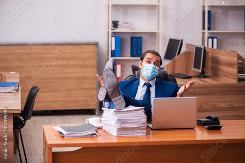 Young male employee working in the office wearing mask
