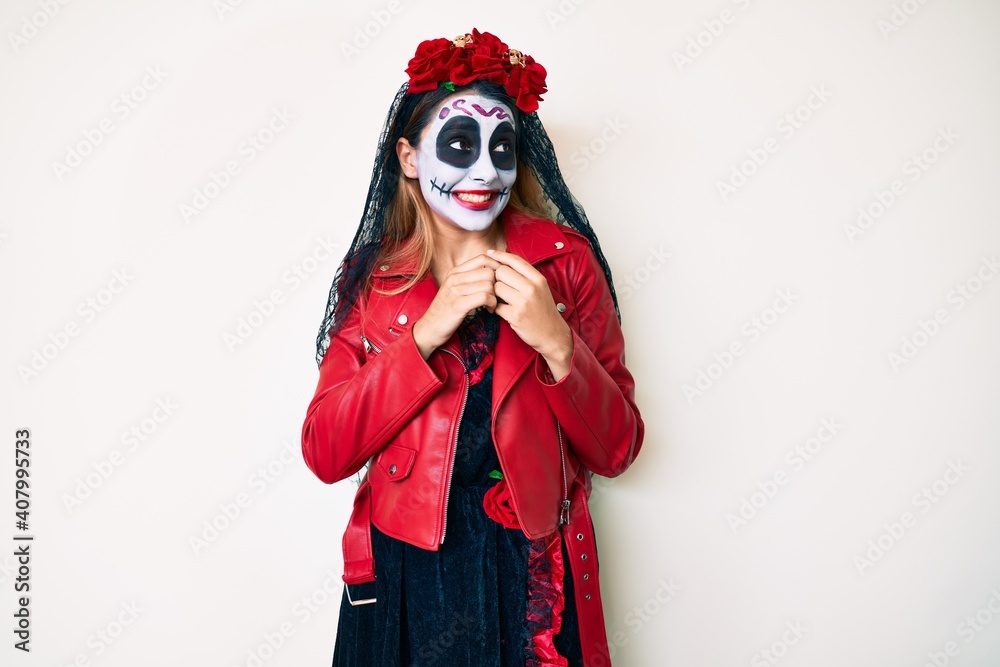 Woman wearing day of the dead costume over white laughing nervous and excited with hands on chin looking to the side Woman wearing day of the dead costume over white laughing nervous and excited with hands on chin looking to the side