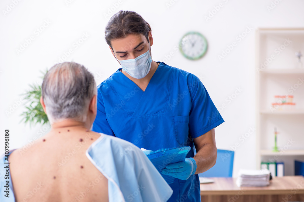Fototapeta premium Old man visiting young male doctor dermatologist