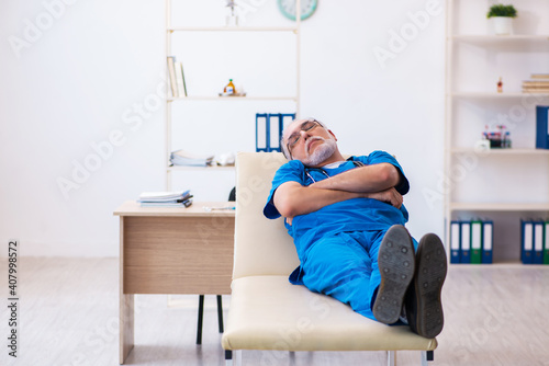 Old male doctor extremely tired after night shift