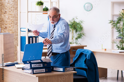 Old male bookkeeper unhappy with excessive work at workplace