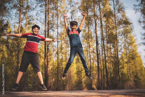 Friendship togetherness outdoor concept  Two diversity asian and caucasian boys brother playing jump in park