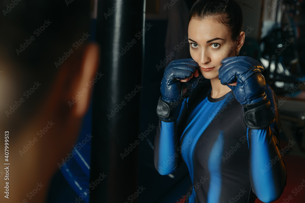 beautiful woman in her thirties trains in boxing gloves in the gym, a couple is engaged in boxing