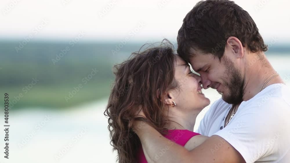 Amazing close up portrait of cheerful caucasian woman with freckles laughing with closed eyes hugging with her man against the sunset outside. Amazing close up portrait of cheerful caucasian woman with freckles laughing with closed eyes hugging with her man against the sunset outside.