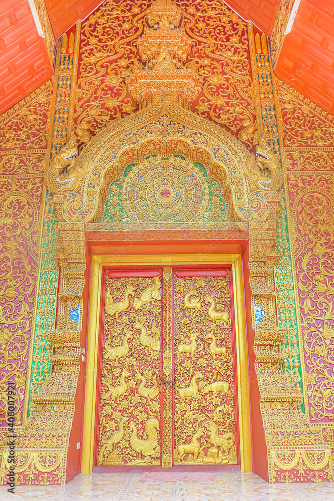 Temple doors facade with traditional Thai decoration and golden glass mosaics in chiang mai, Thailand.