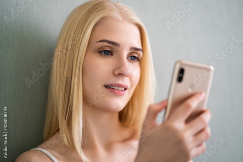 Cute blue-eyed blonde girl watching video on phone