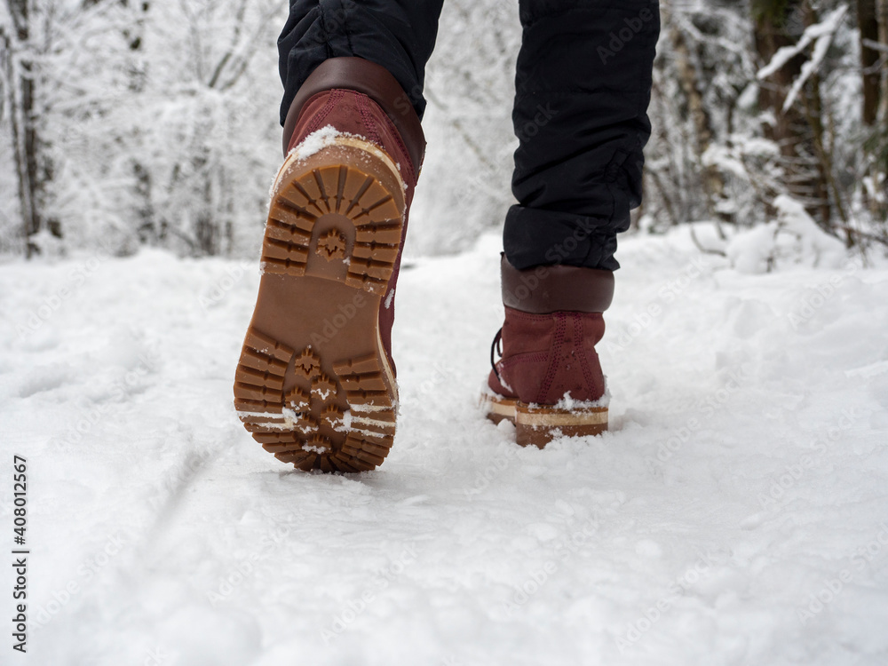 A man in boots is walking through the winter forest. Bottom view of shoes, selective focus. Concept of hikes walks and winter holidays A man in boots is walking through the winter forest. Bottom view of shoes, selective focus. Concept of hikes walks and winter holidays