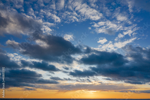 Yellow sunset and puffy clouds in the sky pierced with sun rays. Beautiful nature background.