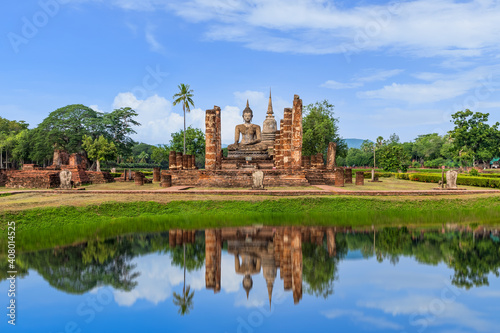 Buddha statue and Pagoda in ruined monastery complex at Wat Mahathat temple with reflection, Sukhothai Historical Park, Thailand © wirojsid