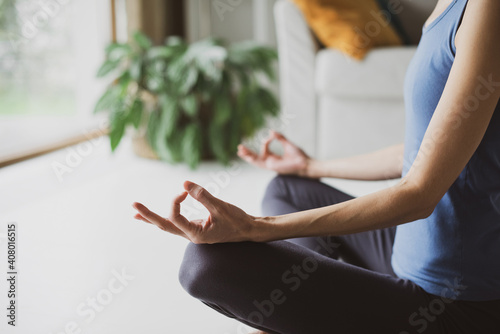 Closeup of young woman meditating and practicing yoga at home. Recreation, self care, yoga training, fitness, breathing exercises, meditation, relaxation, healthy lifestyle concept