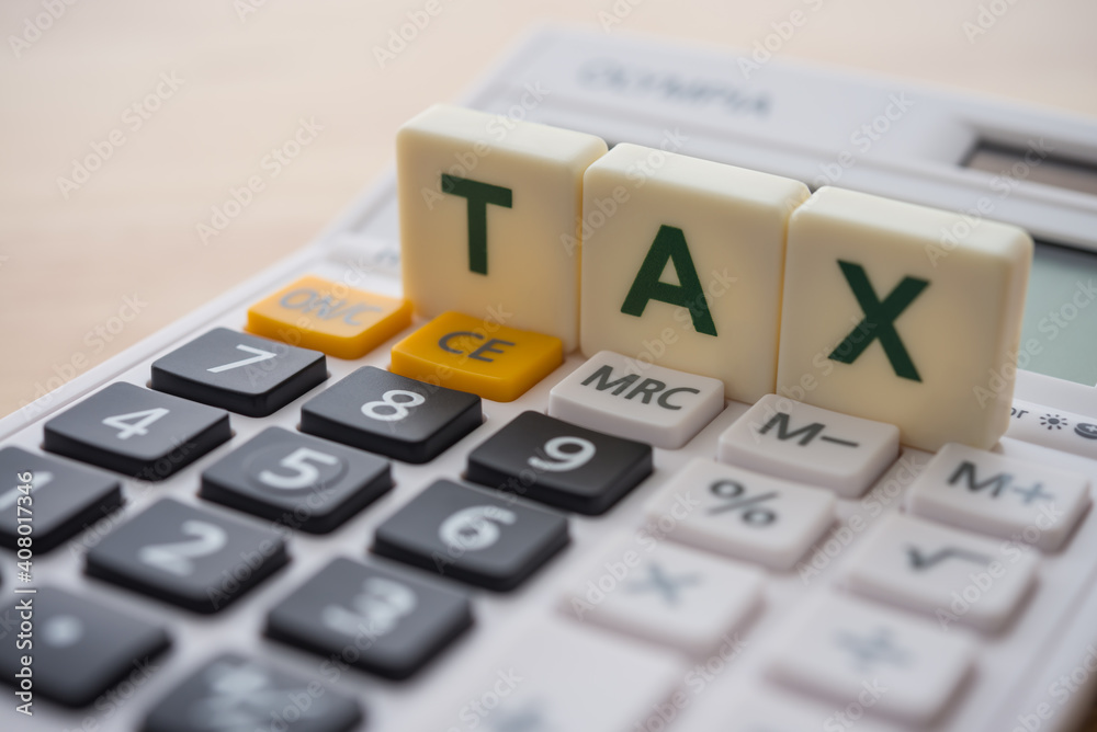 Close up word alphabet TAX on white digital calculator background. Business and financial, tax time or tax payment deadline concept. Close up word alphabet TAX on white digital calculator background. Business and financial, tax time or tax payment deadline concept.