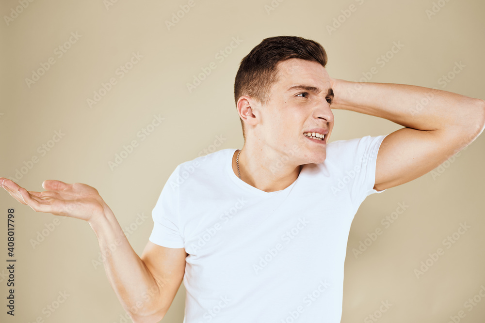Emotional man facial expression gesture with hands white t-shirt beige background Emotional man facial expression gesture with hands white t-shirt beige background
