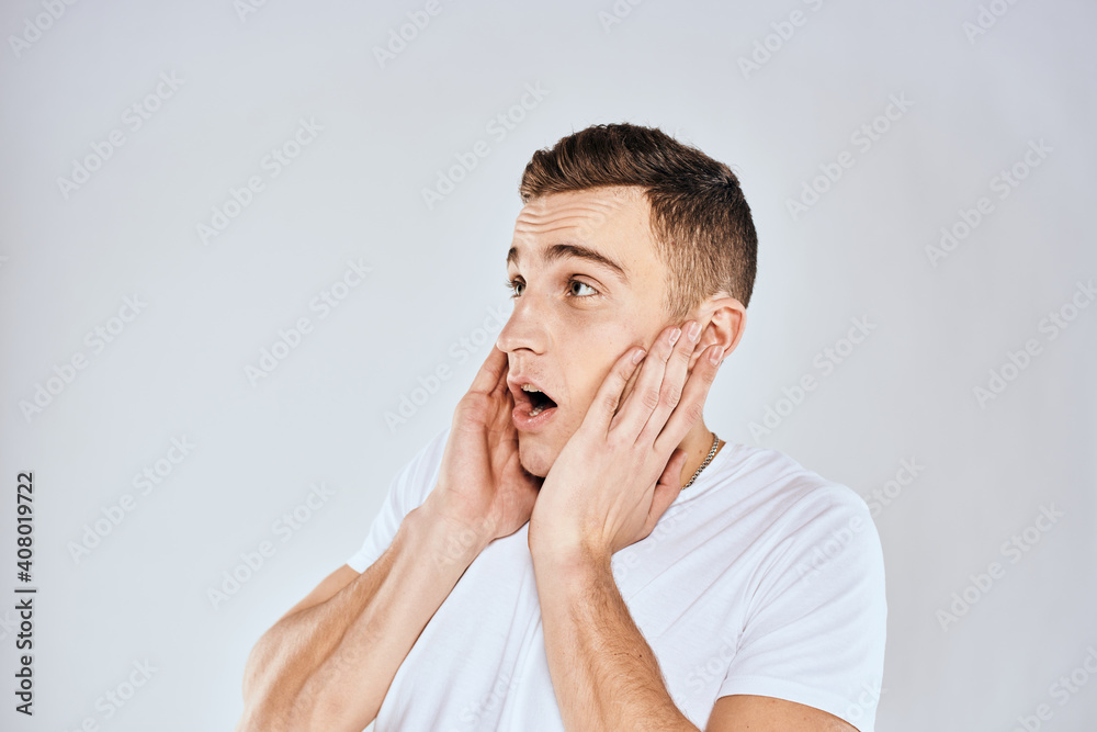 Nice man in a white t-shirt gestures with his hands emotions surprise studio Nice man in a white t-shirt gestures with his hands emotions surprise studio