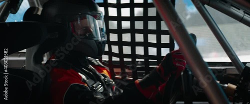 CU Portrait of sports car driver in protective helmet and suit racing on a speedway. Fast speed, motorsport. Daytime shot. Shot with 2x anamorphic lens
