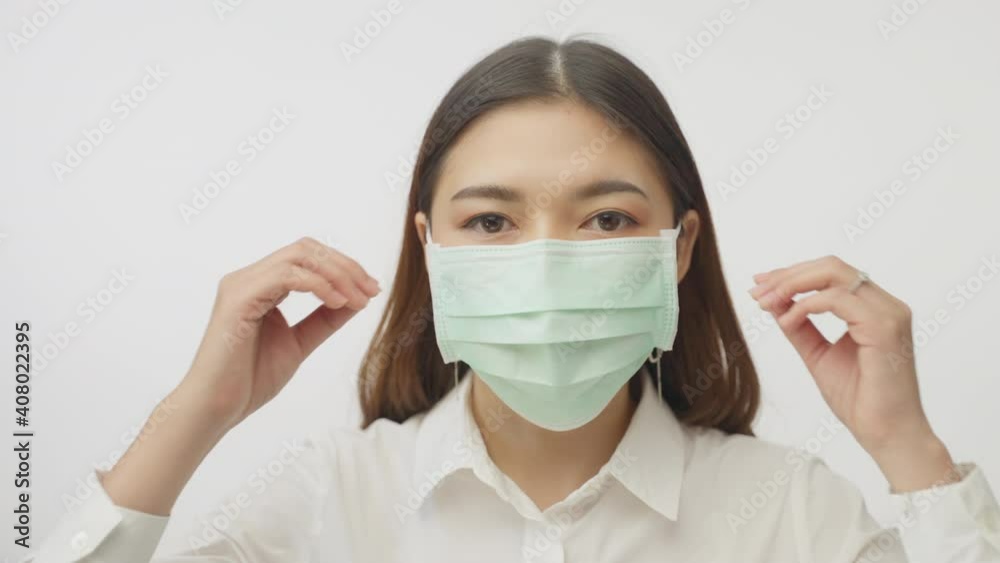 Young businesswoman on white office shirt taking off her surgical mask, with white background filming in slow motion, COVID health protection concept Young businesswoman on white office shirt taking off her surgical mask, with white background filming in slow motion, COVID health protection concept