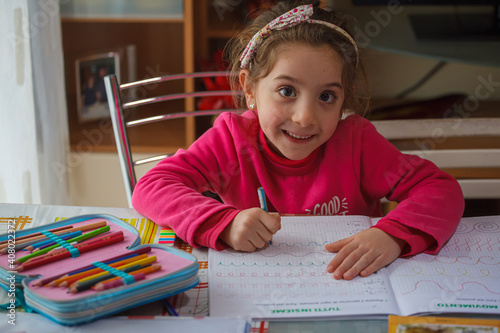 Smiling 6 year old girl does her homework photo