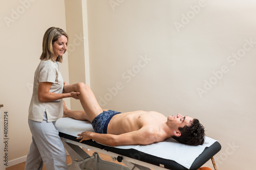 Woman physiotherapist does session to man. Lower extremity mobilizations.