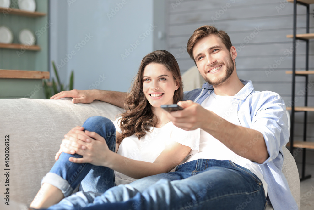 Young loving couple on sofa at home watching tv and laughing. Young loving couple on sofa at home watching tv and laughing.