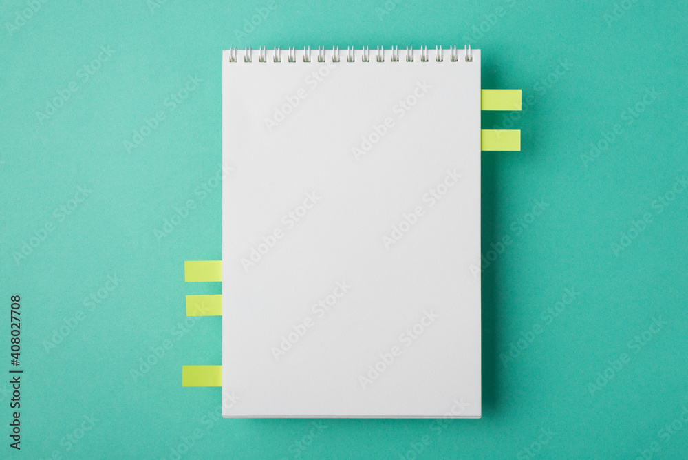 Above flat lay overhead close up view photo image of clear textbook with spiral and memo stickers with copy space isolated teal turquoise desk backdrop Above flat lay overhead close up view photo image of clear textbook with spiral and memo stickers with copy space isolated teal turquoise desk backdrop