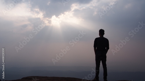 Silhouette of man standing alone on the mountain top looking at sky and sunset view Solo travel and new day inspirational concept