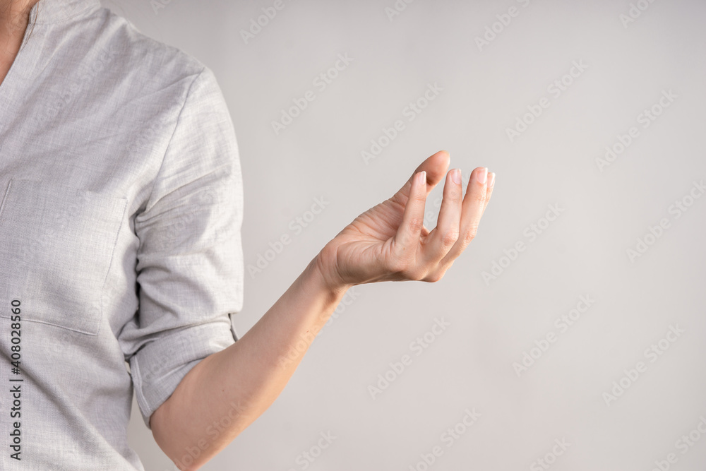 Hold something with your hand while squeezing with your fingers. businesswoman in a casual gray shirt makes a hand gesture