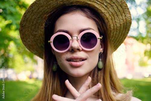Cheerful woman in hat wearing sunglasses outdoors in the park grass walk
