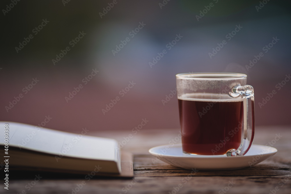 A cup of hot morning coffee on wooden table with a diary notebook at the balcony of the sleeping room to welcome sunshine in the morning, a glass of black coffee with a notebook on the wooden table A cup of hot morning coffee on wooden table with a diary notebook at the balcony of the sleeping room to welcome sunshine in the morning, a glass of black coffee with a notebook on the wooden table